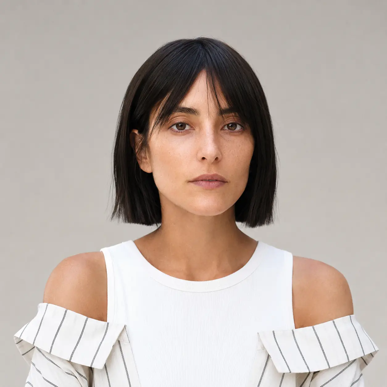 Dark chin-length blunt bob softened with a wispy fringe balancing density on fine hair