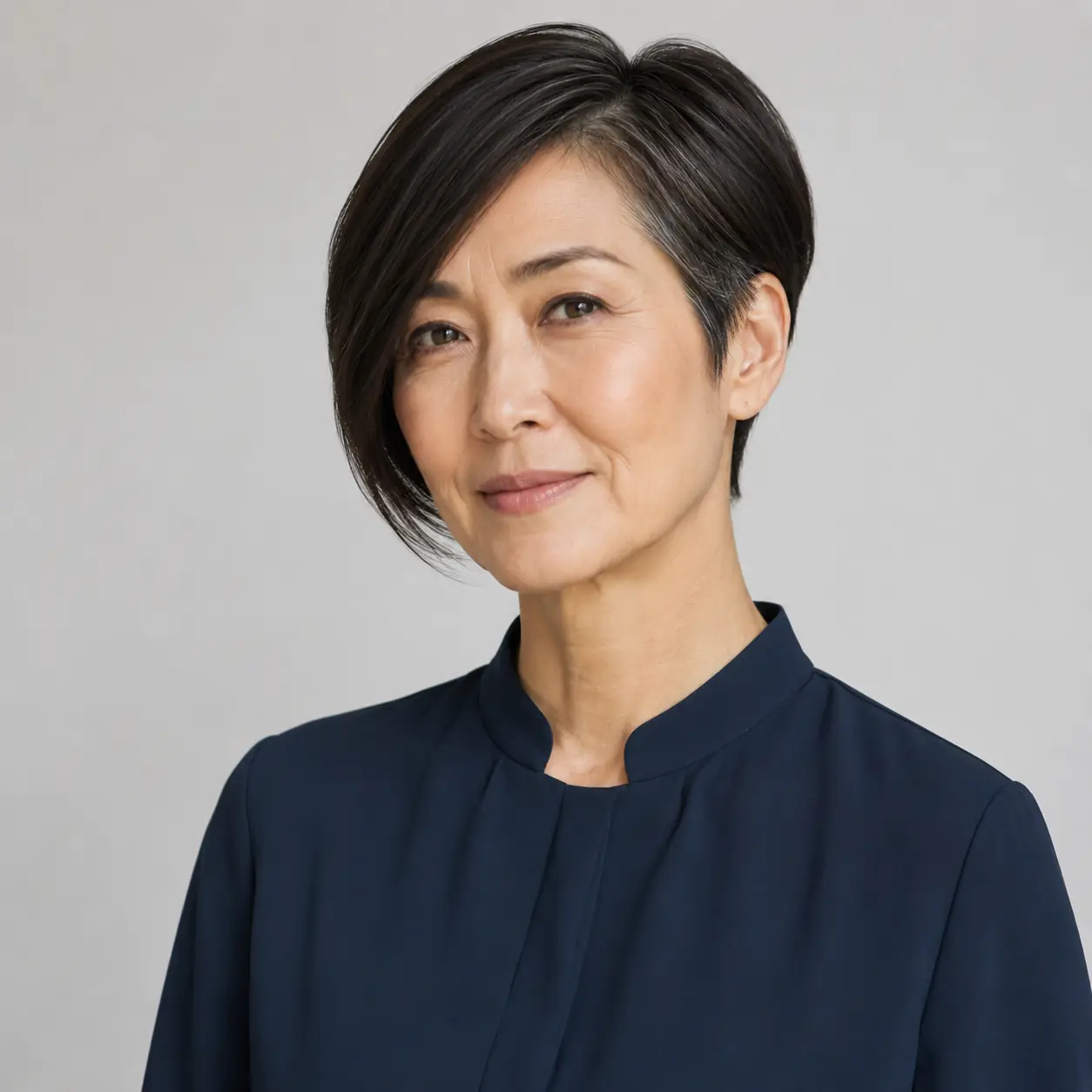 Asymmetrical dark pixie-bob cut longer on one side with a sharp glossy line