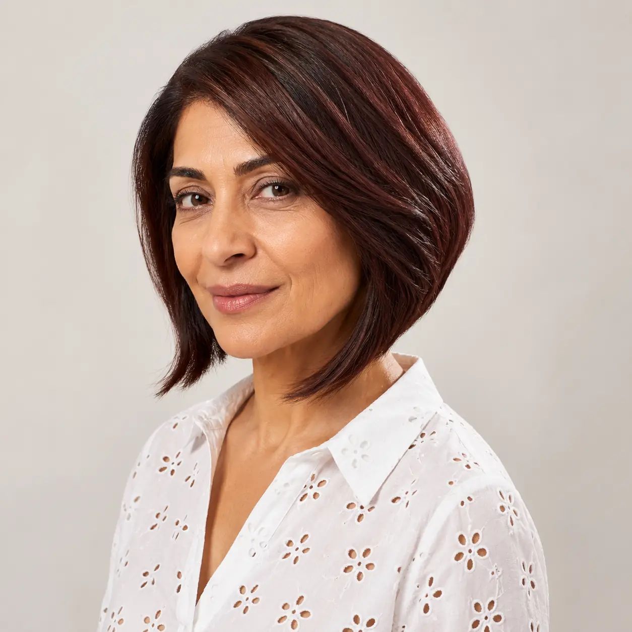 Deep burgundy sleek bob, a bold glossy statement flattering cool undertones over 50