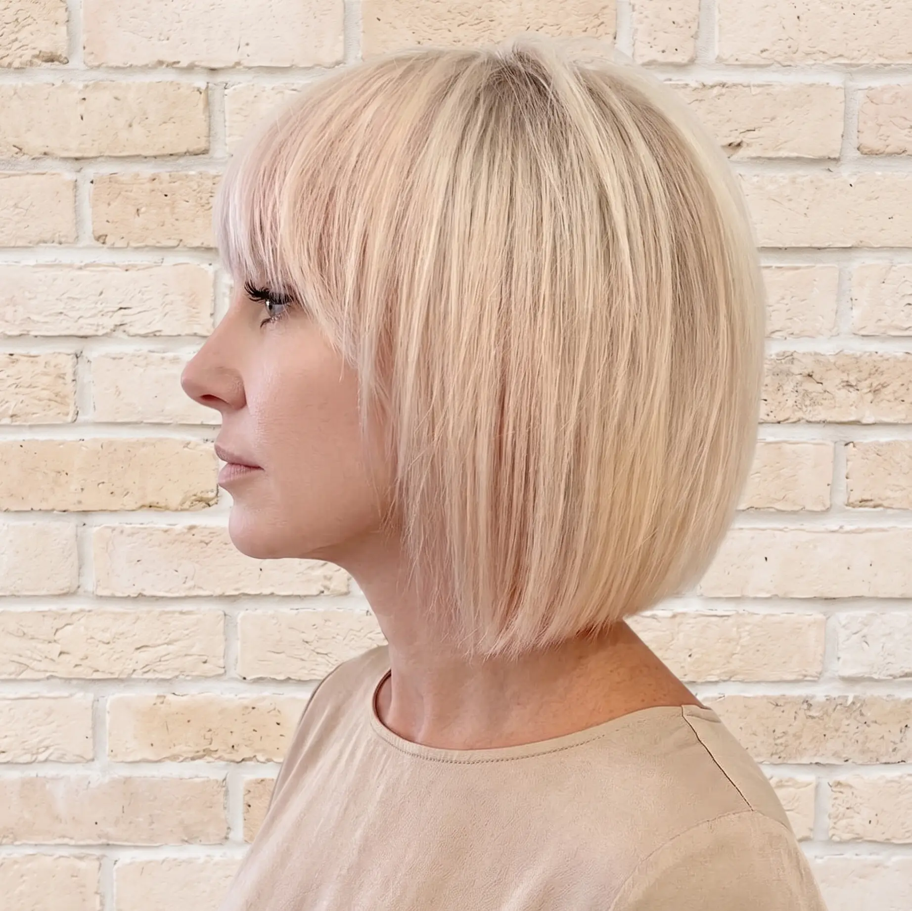 Platinum bob shown in profile with a heavy blunt fringe and a smooth, precise perimeter