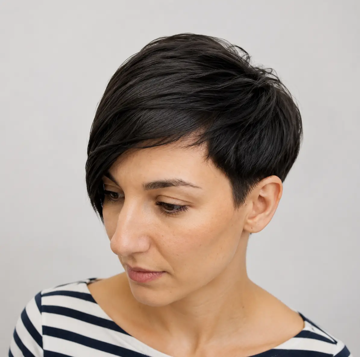 Asymmetrical pixie haircut with one side cut longer than the other adding diagonal lines and edge