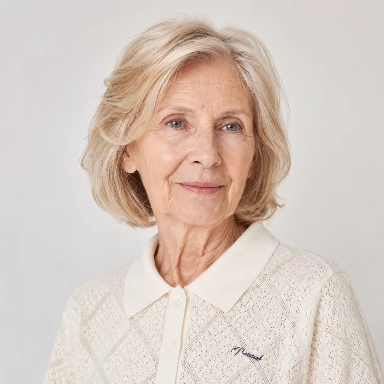 A feathered blonde-gray layered bob with a side part keeps the shape relaxed and elegant on a woman over 70