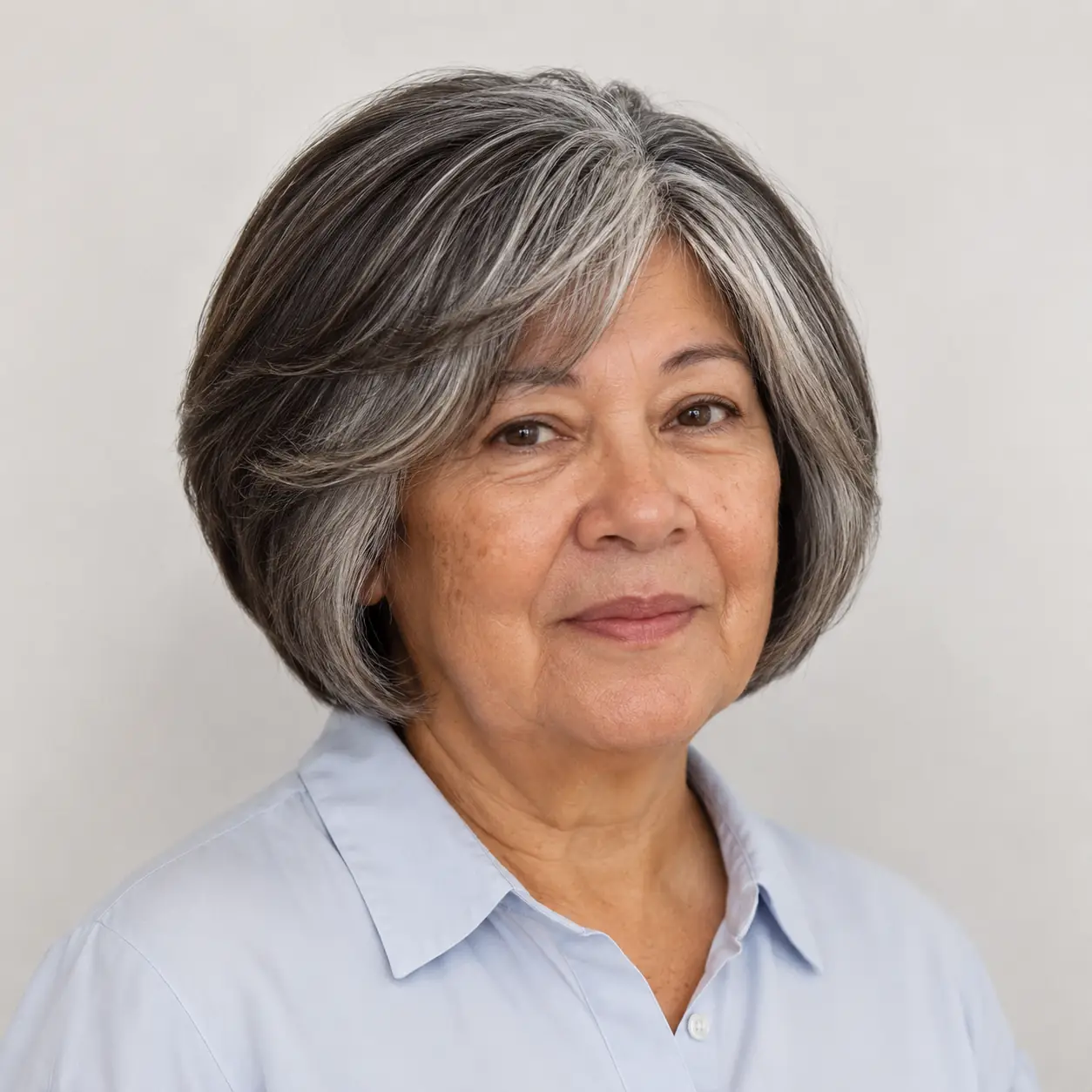 A voluminous chin-length bob swept off the face is a fabulous choice for thick, coarse hair on a woman over 70