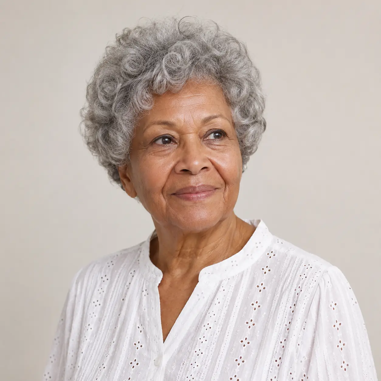 A voluminous curly crop worn close and full celebrates natural coils with height and softness on a woman over 70
