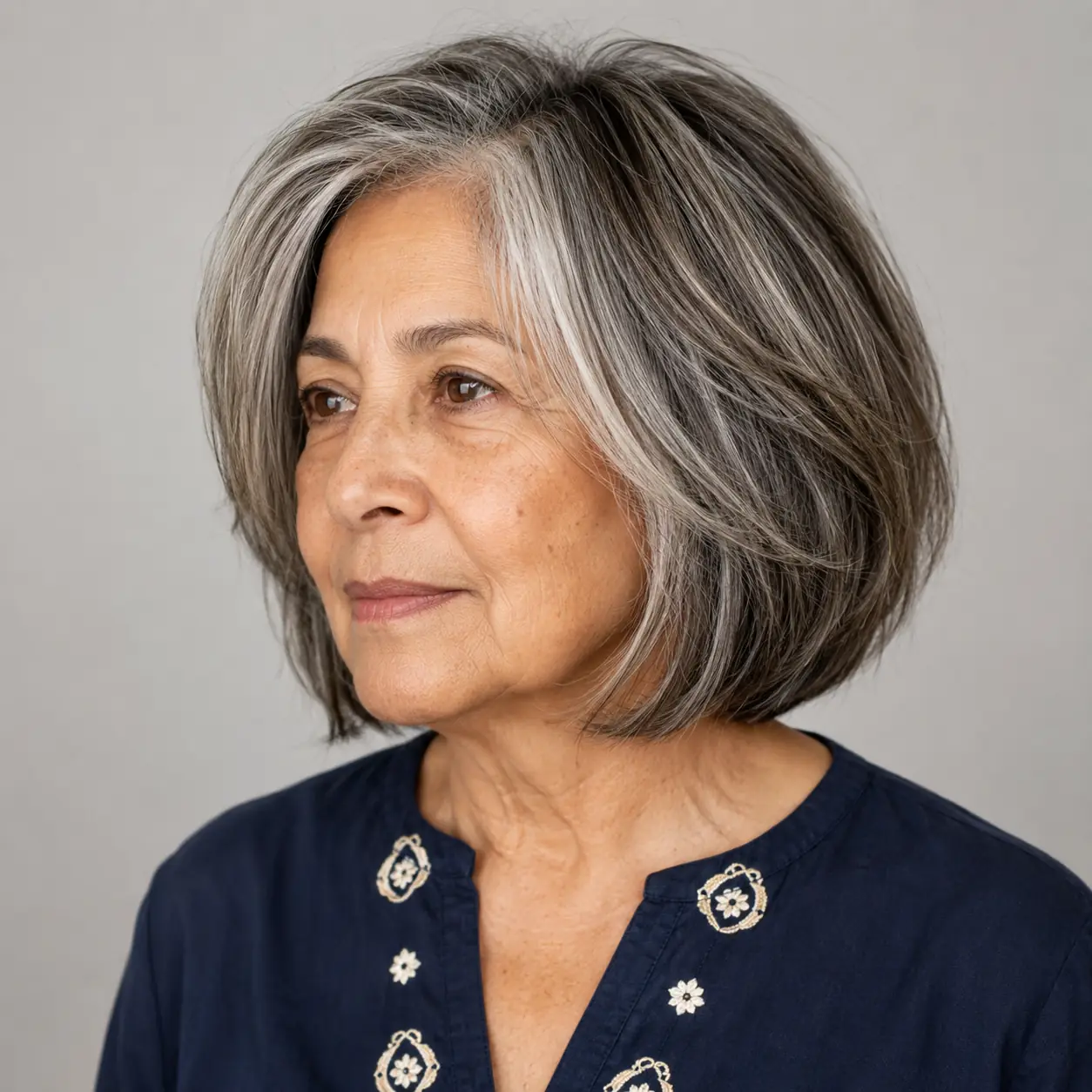 This dark angled bob has a natural silver money piece that lights up the face on a woman over 70